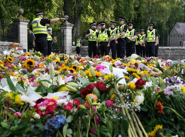 Police officers arrive at the gates of Balmoral in Scotland where flowers and tributes have been laid by members of the public following the death of Queen Elizabeth II. The Queen's coffin will be transported on a six-hour journey from Balmoral to the Palace of Holyroodhouse in Edinburgh, where it will lie at rest. Picture date: Sunday September 11, 2022.