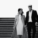 A black and white image of Meghan Markle and Prince Harry walking down a flight of stairs together, hand in hand and smiling (Credit: Netflix) 