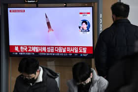 A man watches a television screen showing a news broadcast with file footage of a North Korean missile test, at a railway station in Seoul on December 31, 2022