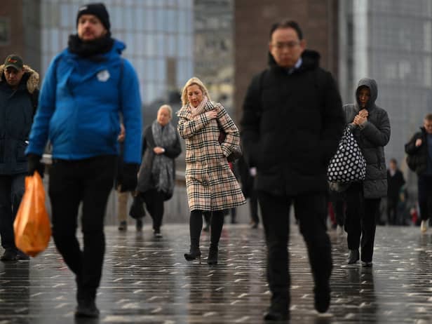 Commuters on their way to work cross London Bridge in central London.