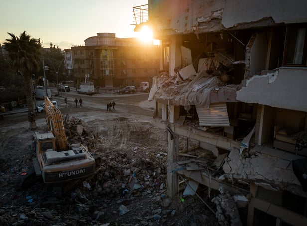<p>Men walk down a street amid rubble from destroyed buildings on February 20, 2023 in Hatay, Turkey</p>