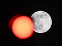 TOPSHOT - This picture taken on February 5, 2023 shows the full moon rising behind a red crossing light in Paris. (Photo by Stefano RELLANDINI / AFP) (Photo by STEFANO RELLANDINI/AFP via Getty Images)