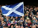 A Scotland fan waves a national flag as they enjoy the pre-match atmosphere prior to a Six Nations Rugby match at Murrayfield Stadium
