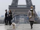 A woman wearing a protective mask walks her dog on the Esplanade du Trocadero square in front of the Eiffel Tower in March 2020 (Photo: Pascal Le Segretain/Getty Images)