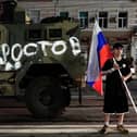 A man holds the Russian national flag in front of a Wagner group military vehicle with the sign read as "Rostov" in Rostov-on-Don late on June 24, 2023. Rebel mercenary leader Yevgeny Prigozhin who sent his fighters to topple the military leaders in Moscow will leave for Belarus and a criminal case against him will be dropped as part of a deal to avoid "bloodshed," the Kremlin said on June 24. (Photo by STRINGER / AFP) (Photo by STRINGER/AFP via Getty Images)