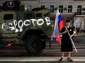 A man holds the Russian national flag in front of a Wagner group military vehicle with the sign read as "Rostov" in Rostov-on-Don late on June 24, 2023. Rebel mercenary leader Yevgeny Prigozhin who sent his fighters to topple the military leaders in Moscow will leave for Belarus and a criminal case against him will be dropped as part of a deal to avoid "bloodshed," the Kremlin said on June 24. (Photo by STRINGER / AFP) (Photo by STRINGER/AFP via Getty Images)