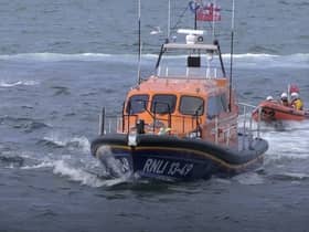 Dolphins swim alongside RNLI lifeboat in Whitby, North Yorkshire. 