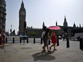 Pedestrians walk in the midday sun past the Palace of Westminster in central London on September 6, 2023 as the late summer heatwave continues.
