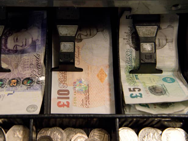 An open cash register containing pound coins and notes is pictured in a convenience store in London