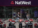 Pedestrians walk past a branch of a NatWest bank in London.