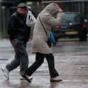 People walk in rain and high winds.