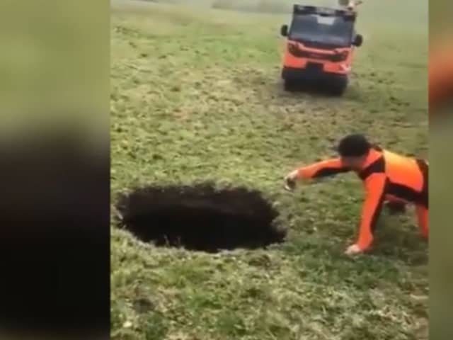 Hiker points to a giant sinkhole estimated to be around 20m deep