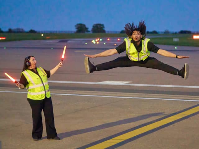 Airport ground handlers perform lively dance routine on runway.