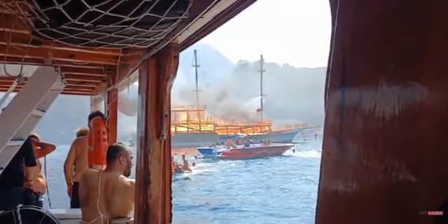 Fire rages through tourist boat as passengers jump into ocean.