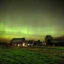 The northern lights fill the sky with green ribbons of electrical charged particles over a barn (Photo by Michael Seamans/Getty Images)