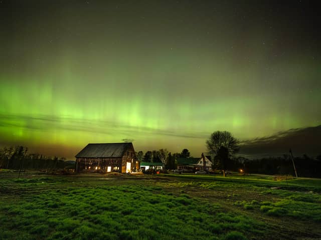 The northern lights fill the sky with green ribbons of electrical charged particles over a barn (Photo by Michael Seamans/Getty Images)