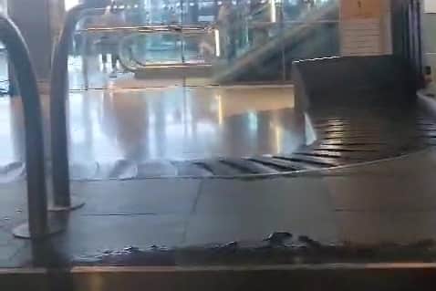 “Sewage” water pours onto baggage carousel at airport.