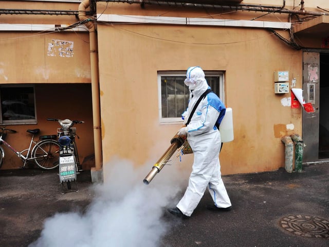A worker wearing a protective suit sprays disinfectant in a neighborhood in Qingdao in eastern China's Shandong Province. (Photo: Chinatopix via AP)