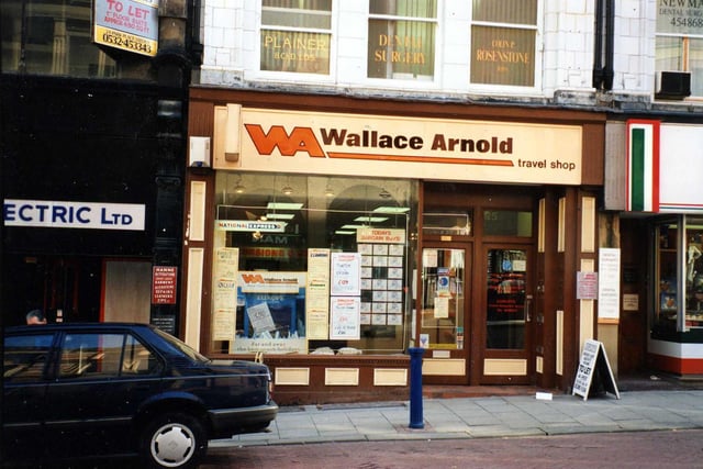 Wallace Arnold travel agents on Albion Place. Above this is a dental surgery. On the left is Regam Electric Ltd and on the right Pasta Romagana.