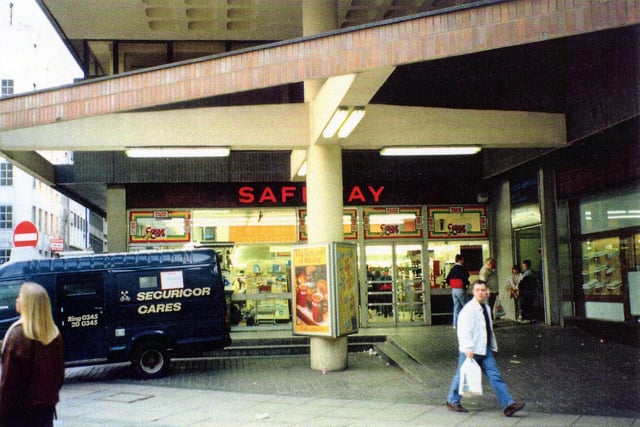 The entrance to Safeway supermarket on Bond Street. Upper Basinghall Street can be seen on the left. On the right is Ainsley's bakers then the entrance to the car park and public amenities.