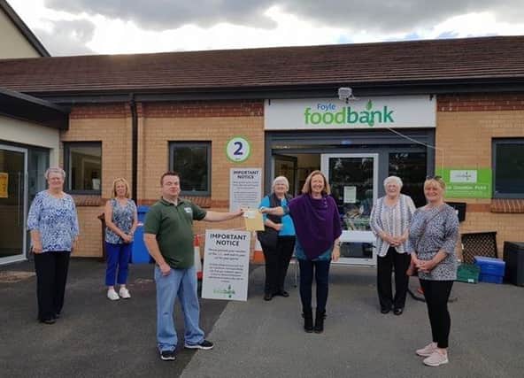Members of the Derry Masks and Scrubs Making Group  Pauline Mullan, Terri Kennedy, , Anne MacCrossan, Aideen Hughes Sally Mullan and Nuala Miller presenting a cheque for £1,262.52 to James McMenamin, Foyle Food Bank
