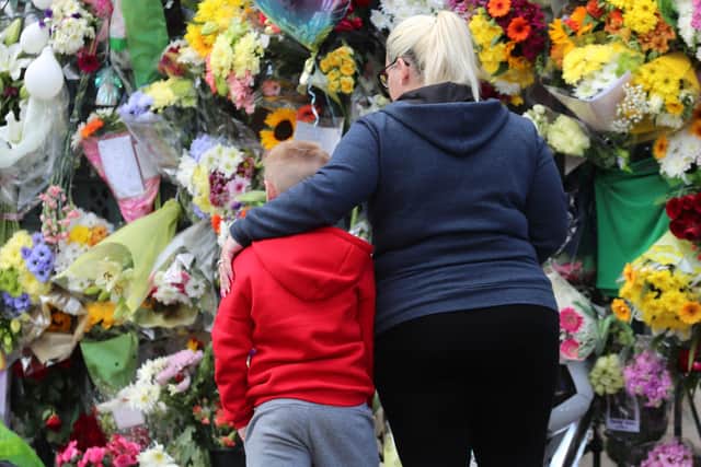 A mother comforts her son as they lay a floral tribute to Noah Donahoe at the gates of his school, St Malachy's College in Belfast