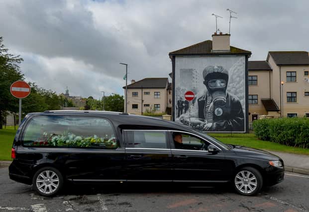 The funeral cortege of Patrick (Paddy) Coyle passes the Gasmask mural in the Bogside on its way to the City Cemetery after Requiem Mass in St Eugene’s Cathedral. Photo: George Sweeney DER2030GS – 001