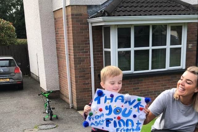Finn shows the cyclists the poster he made for them as he supports them on their 16,000km challenge for his school, Ardnashee.