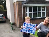 Finn shows the cyclists the poster he made for them as he supports them on their 16,000km challenge for his school, Ardnashee.