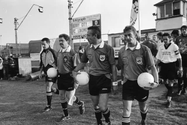 The Belgian match officials lead the teams out at Brandywell Stadium.