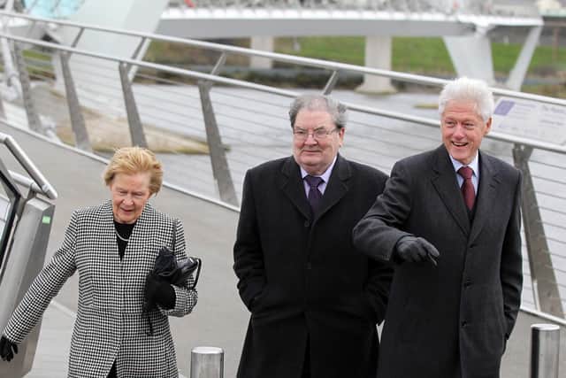 John and Pat Hume and Bill Clinton walk across the Peace Bridge.