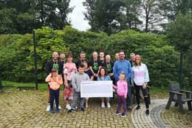 Children and staff from Ardnashee School and College and members of the PTA are presented with a cheque for £15,000 by a group of cyclists who cycled over 16,000km.