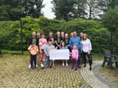 Children and staff from Ardnashee School and College and members of the PTA are presented with a cheque for £15,000 by a group of cyclists who cycled over 16,000km.