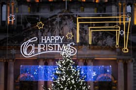 Christmas lights with the cranes of Harland and Wolff hanging above a street in front of Belfast City Hall.