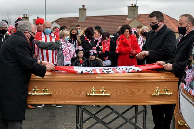 The Brandywell Pride Supporters Club flag is removed from the coffin of Hugh Curran prior to Requiem Mass in St Mary’s Church Creggan on Wednesday morning. Photo: George Sweeney / Derry Journal DER2050GS – 034