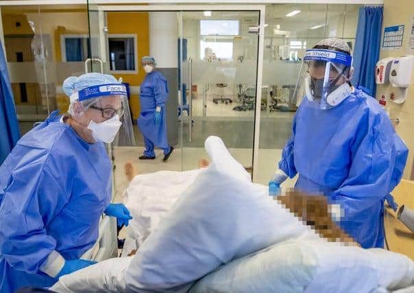 Health workers wearing full personal protective equipment (PPE) tend to a patient on the intensive care unit (ICU).