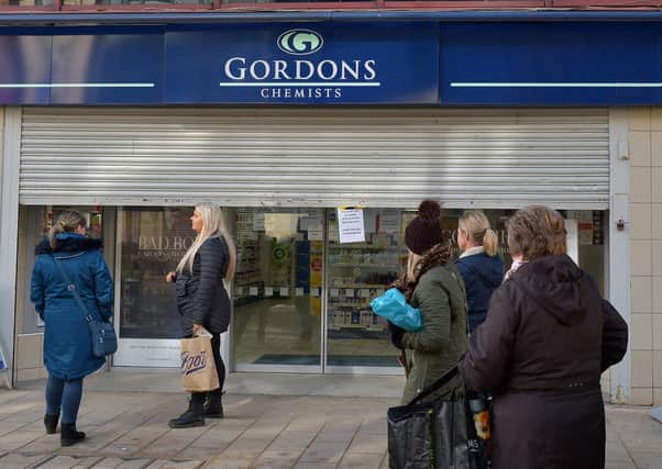 Exemplary: Local people queuing patiently outside Gordon’s Chemist on Strand Road in Derry on Wednesday. (Pictures by George Sweeney)