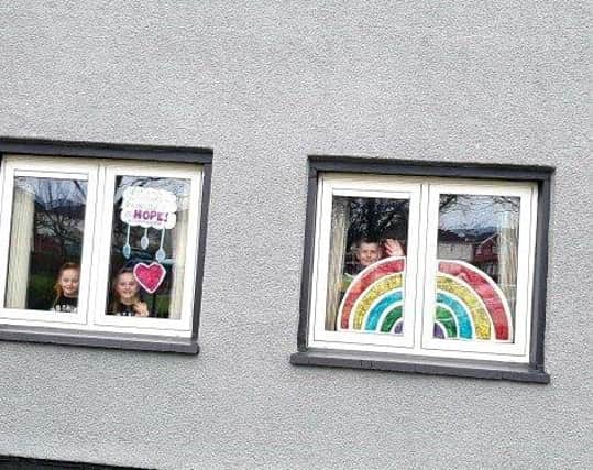 Clodagh, Aobheann and Shea O'Mora with the rainbows of hope they created for their Creggan home