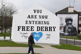 A man walks his dog past a message of support for the NHS on the Free Derry Corner.