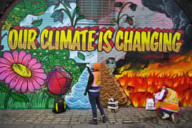 Artists paint a mural on a a wall next to where the COP26 UN Climate Summit will take place in November.