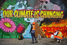 Artists paint a mural on a a wall next to where the COP26 UN Climate Summit will take place in November.