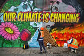 Artists paint a mural on a a wall next to where the COP26 UN Climate Summit will take place in November.