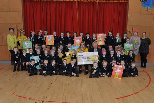 St. Patrick’s Primary School principal Mr. Eamonn Devlin presents former pupil and Children In Need Surprise Squad member Roisin Quinn with a £500 cheque donation for Children In Need at the school on Friday morning last. Included in the photograph are staff and pupils dressed for their ‘Mad Hair Day’. DER2146GS – 005