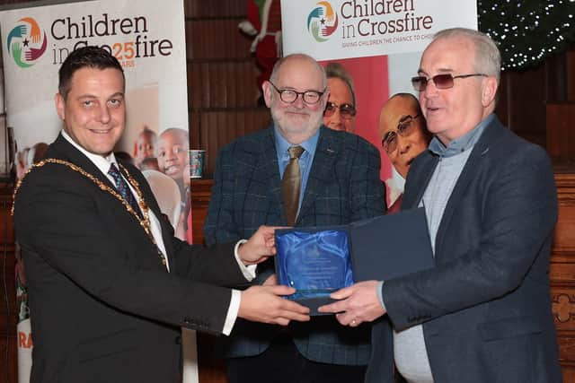 Mayor Graham Warke presents a gift to Richard Moore, founder of Children in Crossfire, at an event to mark the 25th anniversary of Children in Crossfire, held in the Guildhall.  Included is Marcus O'Neill, chairperson, Children in Crossfire. (Photo - Tom Heaney, nwpresspics)