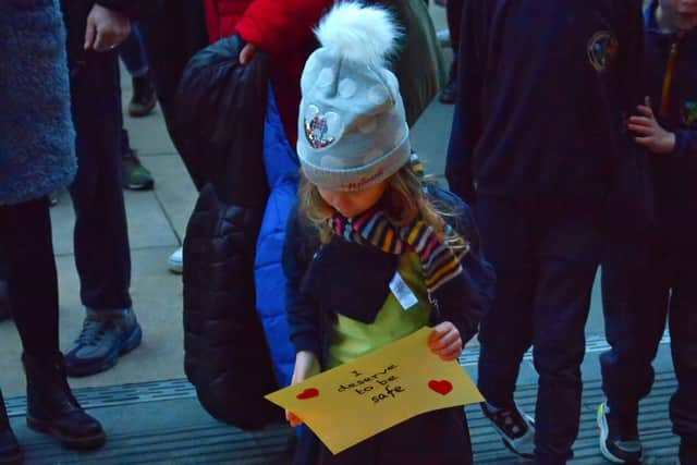 A young girl attending the vigil for Ashling Murphy places a message on the Guildhall Steps on Friday afternoon. Photo: George Sweeney.  DER2202GS – 082