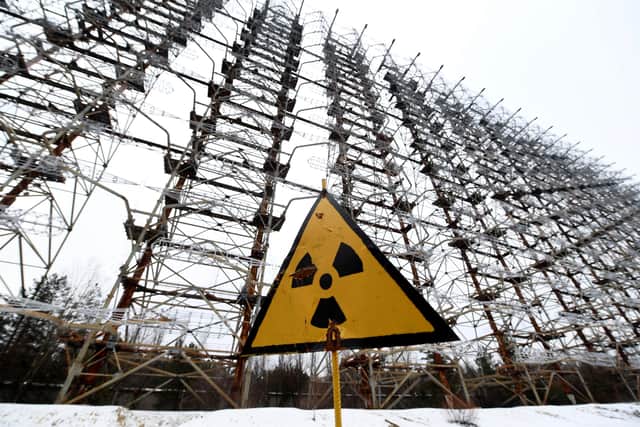 A sign with the radiation warning symbol is seen in front of the construction of the 'Duga' Soviet over-the-horizon (OTH) radar system near Chernobyl on November 22, 2018. - The radar, which was a part of the former Soviet Union missile defence radar system and is now located in the Chernobyl Exclusion Zone, was closed after the Chernobyl catastrophe in 1986. (Photo by Sergei SUPINSKY / AFP)        (Photo credit should read SERGEI SUPINSKY/AFP via Getty Images)