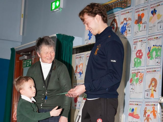 Donncha Gilmore, Steelstown Brian Ogs, receives a gift from Greenhaw's Primary 1 pupil Charlie Harkin, ably assisted by Ms. Heaney, during his recent visit. (Photo: Jim McCafferty)