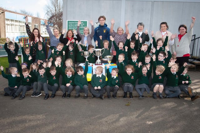 Primary 1 pupils and staff at Greenhaw Primary School with Brian Ogs player Donnacha Gilmore and the trophies won this season by the local club. (Photos: Jim McCafferty Photography)