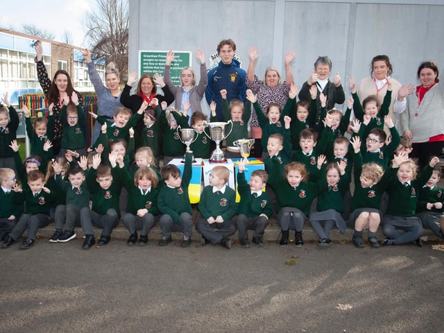 Primary 1 pupils and staff at Greenhaw Primary School with Brian Ogs player Donnacha Gilmore and the trophies won this season by the local club. (Photos: Jim McCafferty Photography)