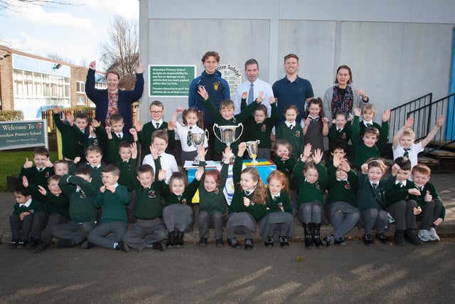 Primary 2 pupils and staff at Greenhaw Primary Schoolwith Brian Ogs player Donnacha Gilmore and the trophies won last season by the local club.  (Photos: Jim McCafferty Photography)